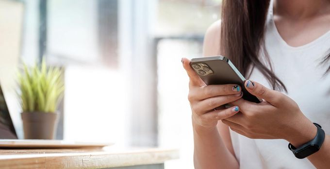 Businesswoman using her smart phone in office. Female entrepreneur looking at her mobile phone. Reading text messages.