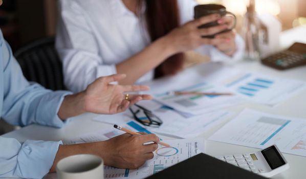 Businesswoman holding pens and holding graph paper are meeting to plan sales to meet targets set in next year..