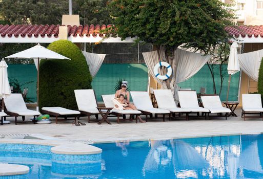 Happy family and healthy lifestyle. Young mother with small child near the pool are resting at the resort