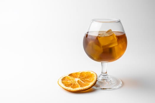 a glass of whiskey with ice and a slice of orange on a white background. High quality photo