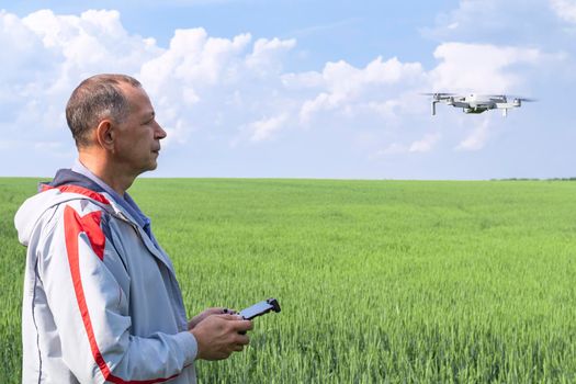 aerial photography of agricultural crops . a man with a quadrocopter on the background of a field and a blue sky. High quality photo