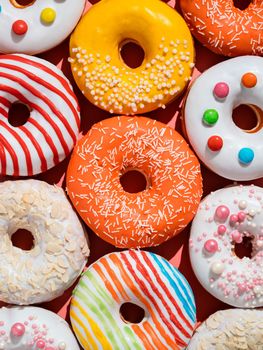 Assorted colorful glazed donuts with sprinkle. Creative layout made from delicious glazed donuts. Vertical flat lay background with multicolored donuts or doughnuts