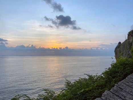 A scenic Uluwatu cliff with pavilion and blue sea in Bali - stock photo