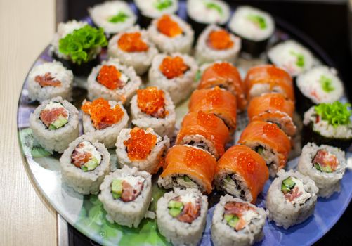 Making sushi and rolls at home. Sushi with seafood, salad and white rice. Food for family and friends. A set of different rolls and sushi on a tray.