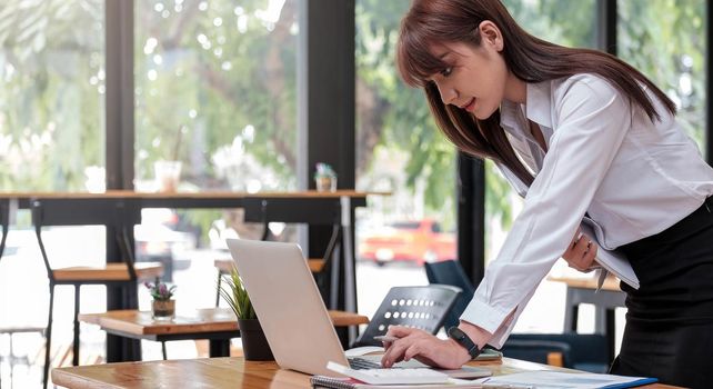 Smart businesswoman analyzing business data, reviewing profits report and working on laptop computer with calculator on desk in office, startup business, business strategy analysis concept, close up.