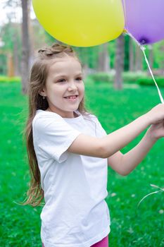 pretty preschool girl having fun playing with hot air balloons outdoors. hollidays, party, birthday, celebration. happy children.