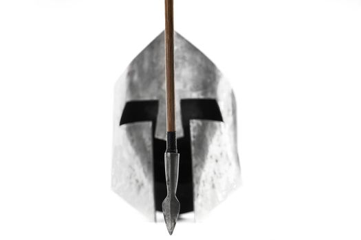 Selective focus of sharp wooden arrow, medieval iron silver helmet on background. Old ancient armour and weapon isolated on white, nobody.
