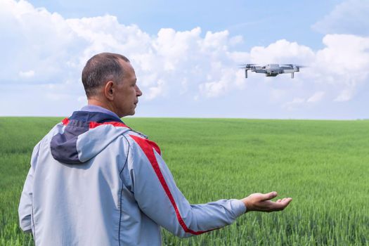 aerial photography of agricultural crops . a man with a quadrocopter on the background of a field and a blue sky. High quality photo