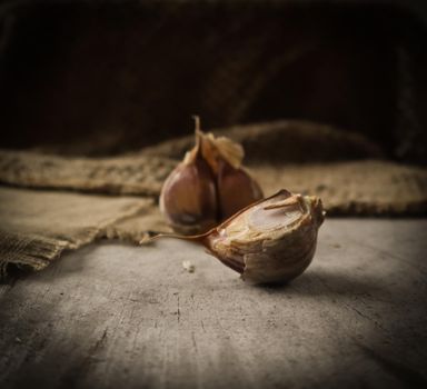 Garlic cloves and natural linen napkin on rustic wooden background