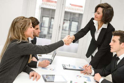 Four business people shaking hands, finishing up a meeting