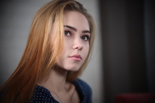 Portrait of beautiful young woman with blonde hair looking above the camera over lights in background. Portrait