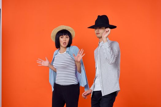 man and woman in hats posing fashion orange background. High quality photo