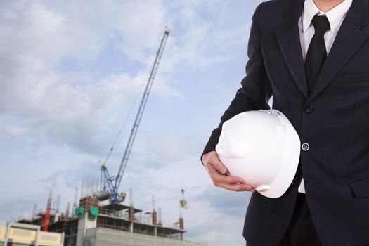 engineer holding white helmet with construction crane background