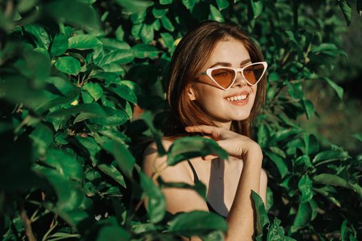 smiling woman wearing sunglasses green leaves nature fashion. High quality photo