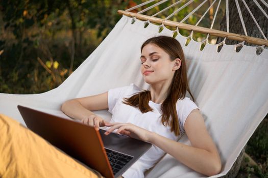 woman working on laptop in nature hammock freelance. High quality photo