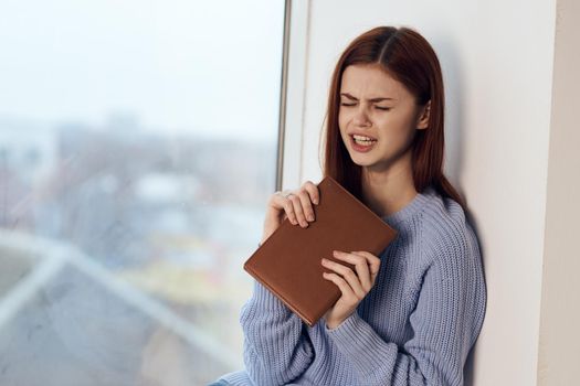 woman reading a book near the window with a cup of drink rest. High quality photo