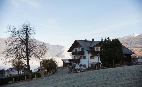Dolomites. A beautiful house with a huge mountains and fog on a background. Mid shot