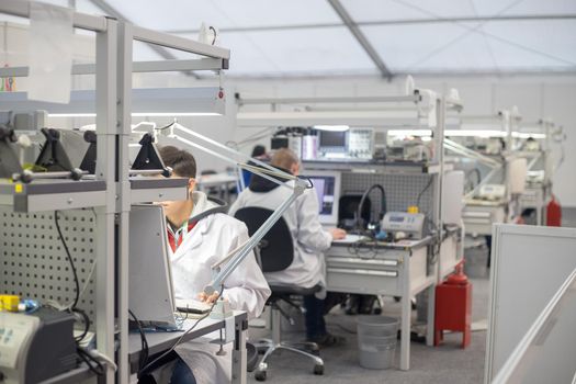 People wearing white coats sitting in the light laboratory at the computers and conduct experiments