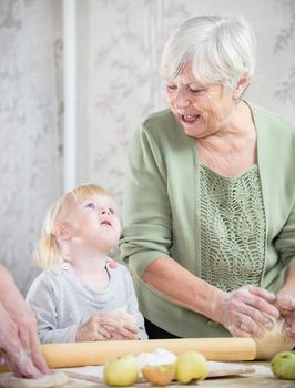 A grandmother making little pies with a little girl. Mid shot
