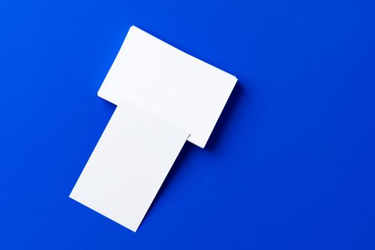 Blank white businesscards on classic blue background, copy space