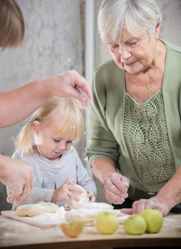 A grandmother making little pies with her granddaughter. Mid shot