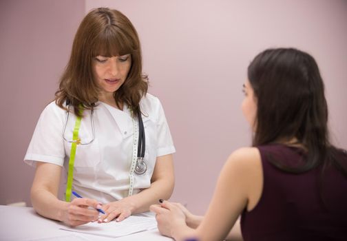 cosmetology beauty clinic. doctor and patient talking to each other. the doctor taking notes