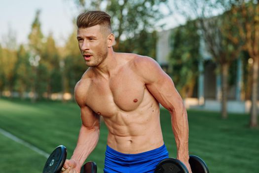 sporty man with pumped up body in park workout exercise. High quality photo