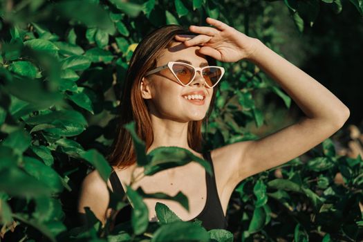 smiling woman wearing sunglasses green leaves nature fashion. High quality photo