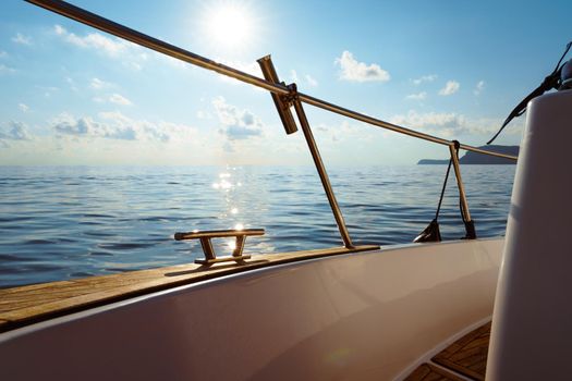 Deck of white yacht sailing in open sea at sunset, close up