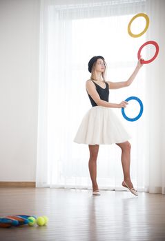 Girl in a hat juggles with rings in the studio, elephoto shot