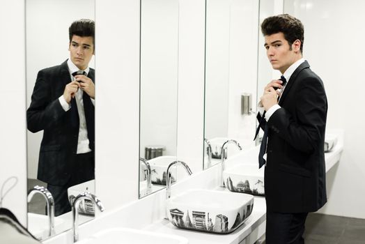 Portrait of a man getting dressed in a public restroom with mirror