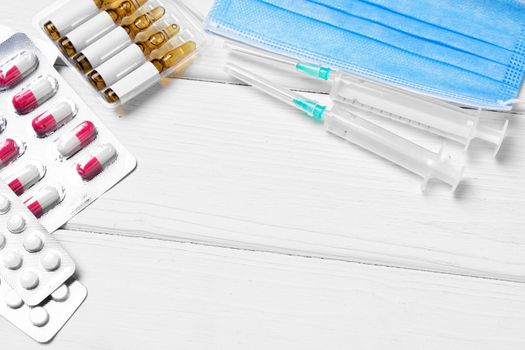 Medical capsules, ampules and face masks close up on wooden background