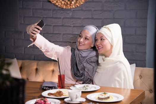 Two Muslim girlfriends are photographed at a table in a cafe, telephoto shot