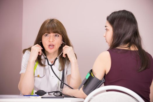 cosmetology beauty clinic. doctor cheking patient's blood pressure and talking to her