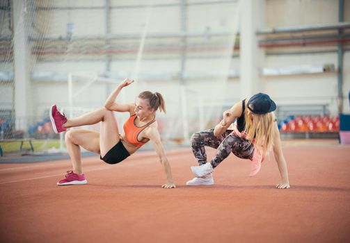 Two young athletic woman working out. Synchronously make movements. Mid shot