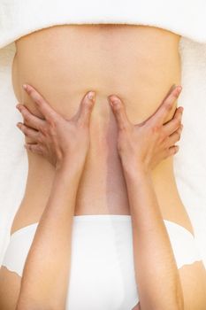 Top view of woman receiving a back massage in a physiotherapy center. Female patient is receiving treatment by professional therapist.