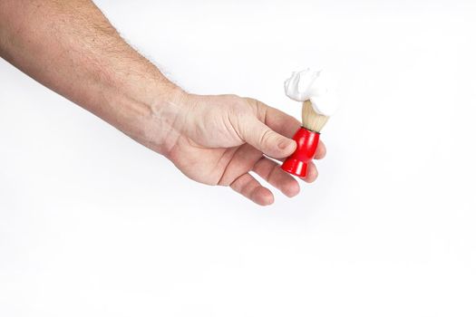 Hand holds a shaving brush with shaving foam on a white background, a template for designers.
