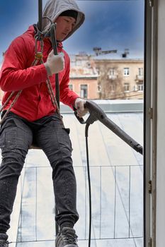 A window washer in climbing gear hangs in the window opening, seen from inside the building