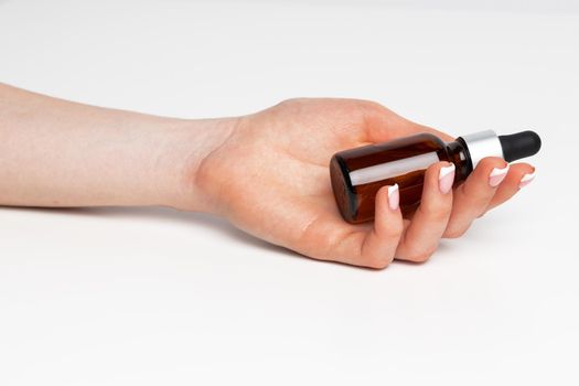 Female hand holding cosmetic bottle on white background