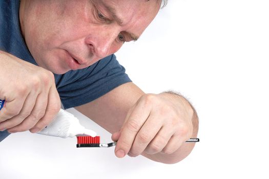 Man squeezes toothpaste onto black toothbrush with red shield on white background