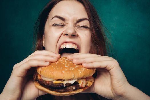 cheerful woman with hamburger near face snacking fast food. High quality photo