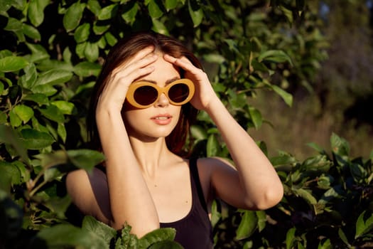 pretty woman in black swimsuit sunglasses green leaves nature. High quality photo