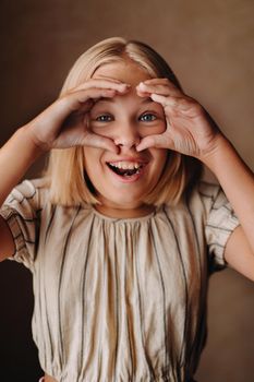 A happy child, a little girl in a gray T-shirt on a beige background.