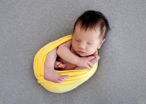 Lovely newborn sleeping wrapped up in yellow blanket