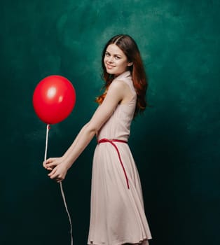 pretty woman in dress red balloon holiday green background. High quality photo