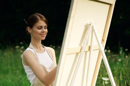 woman artist paints a picture near easel outdoors landscape creative. High quality photo