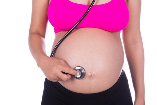 close-up of pregnant woman with stethoscope listening belly to baby