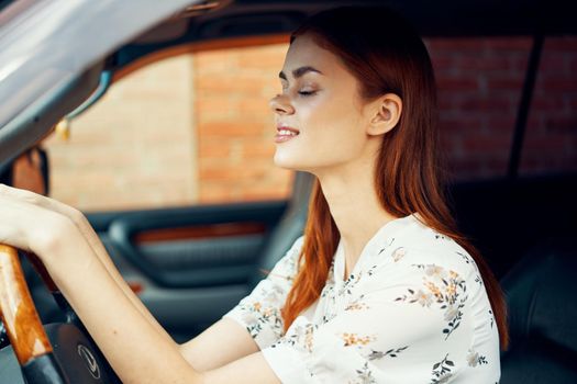 cute red-haired woman driving a car lifestyle trip. High quality photo