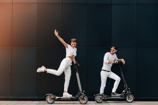 A girl and a guy are walking on electric scooters around the city, a couple in love on scooters