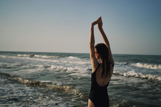 woman in black swimsuit walking on the beach ocean summer. High quality photo